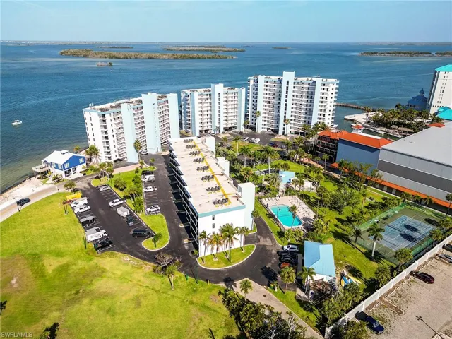 Waterfront high-rise community featuring multiple residential towers, a multi-story parking structure, two swimming pools, and tennis courts