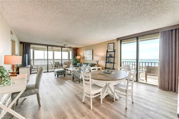 Open-concept living area with wood-finish flooring, a dining space, and a sliding glass door to an outdoor balcony