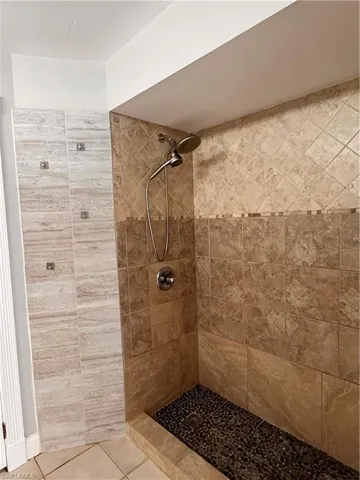 Tiled shower enclosure featuring a pebble mosaic floor