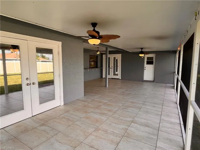 Expansive screened patio featuring wood-finish ceiling fans, light-toned floor tiles, and a stucco-finish exterior wall