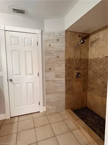 Tiled shower featuring a stone pebble base and a multi-setting showerhead