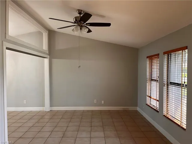 Spacious room featuring vaulted ceilings, tile flooring, and two windows with wood-finish blinds