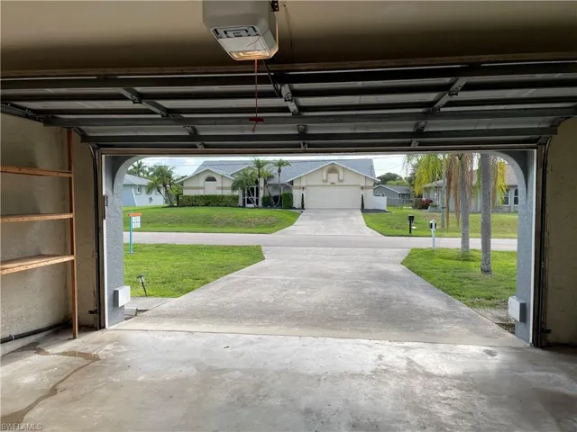 Garage interior featuring a concrete floor, built-in wooden shelving, and an automatic garage door opener