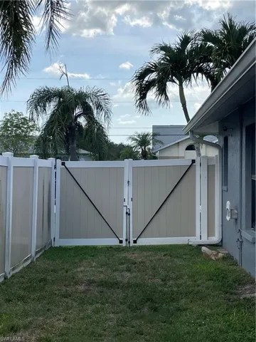 Two-tone privacy fencing with a double gate, featuring black diagonal bracing and hardware