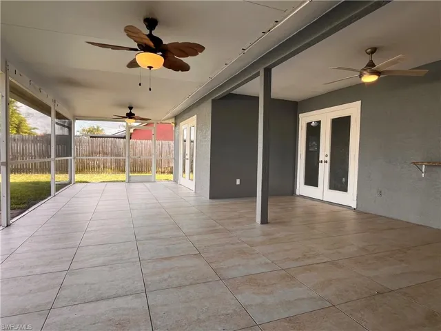 Expansive screened patio featuring large format tile flooring, multiple ceiling fans with integrated lighting, and direct access through double French doors