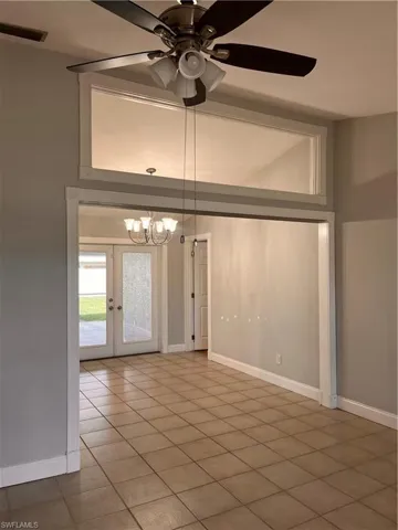 Open concept room featuring large square tile flooring, a ceiling fan with integrated lighting, and crown molding