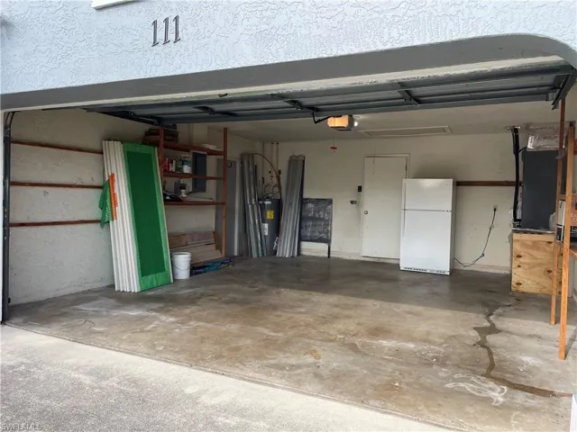 Attached garage with a concrete floor, interior access door, and overhead lighting