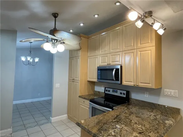 Kitchen featuring light wood-finish cabinetry, stainless steel appliances, and a granite-style countertop