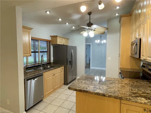 Kitchen featuring light wood-finish cabinetry, stainless steel appliances, and a double basin sink with a gooseneck faucet