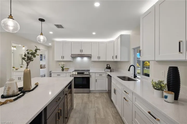 Kitchen featuring white cabinetry, stainless steel appliances, light hardwood / wood-style floors, pendant lighting, and sink