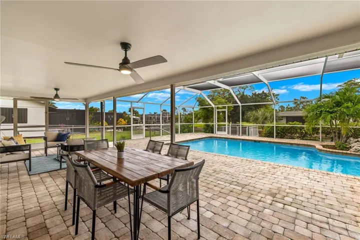 View of swimming pool with a patio, ceiling fan, and glass enclosure