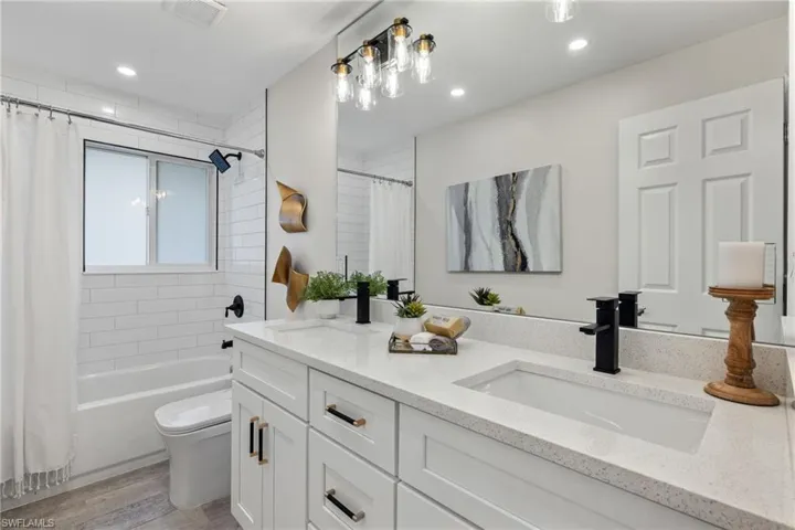 Full bathroom featuring shower / tub combo with curtain, toilet, wood-type flooring, and dual bowl vanity