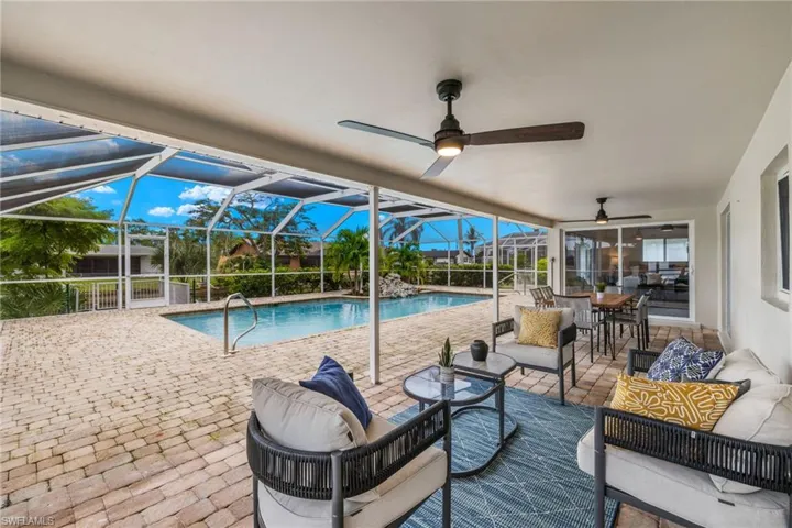 View of swimming pool with a patio, ceiling fan, glass enclosure, and an outdoor hangout area