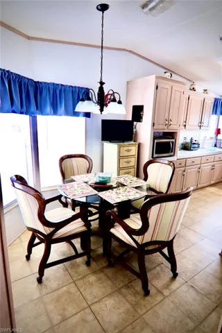 Dining space with vaulted ceiling, a chandelier, light tile patterned floors, and ornamental molding