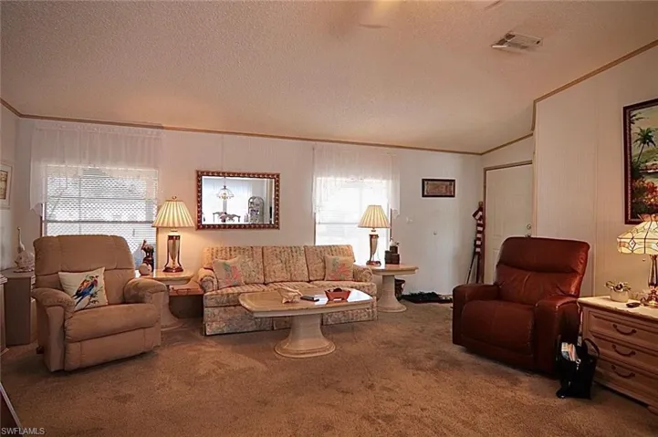 Carpeted living area featuring a textured ceiling and ornamental molding