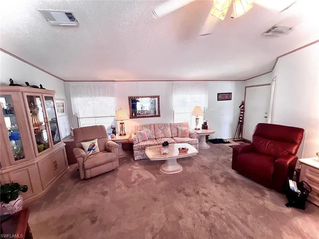 Living room with crown molding, carpet, and a textured ceiling