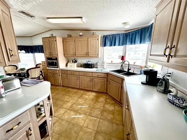Kitchen featuring a sink, plenty of natural light, light countertops, a textured ceiling, and vaulted ceiling