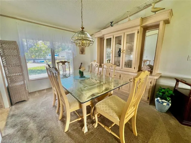 Carpeted dining room with a chandelier and a textured ceiling