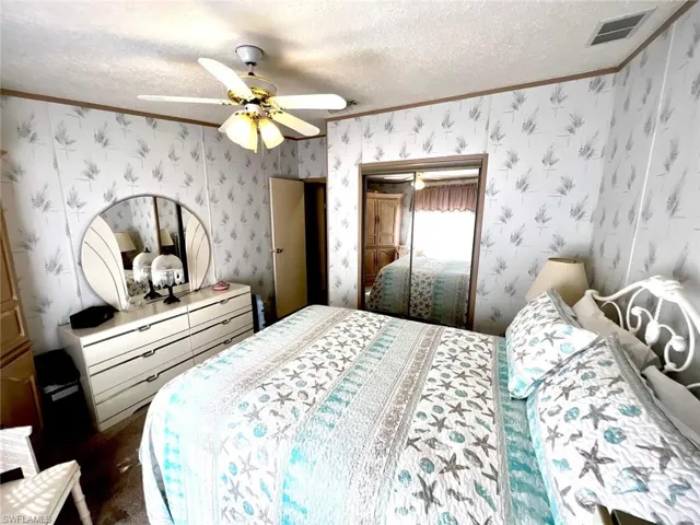 Bedroom with crown molding, a textured ceiling, a ceiling fan, and a closet