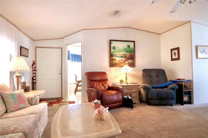 Carpeted living room featuring lofted ceiling and crown molding