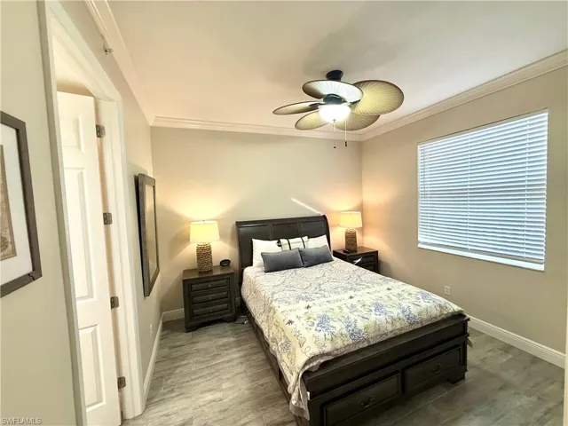 Bedroom with light wood finished floors, ornamental molding, and ceiling fan