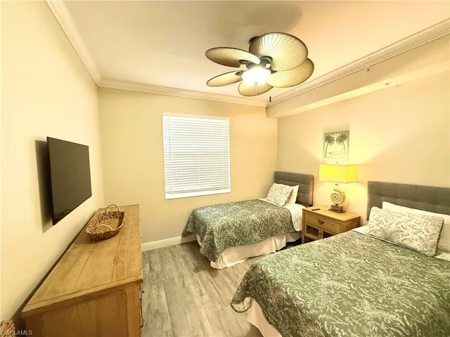 Bedroom with ornamental molding, ceiling fan, and light wood-style flooring