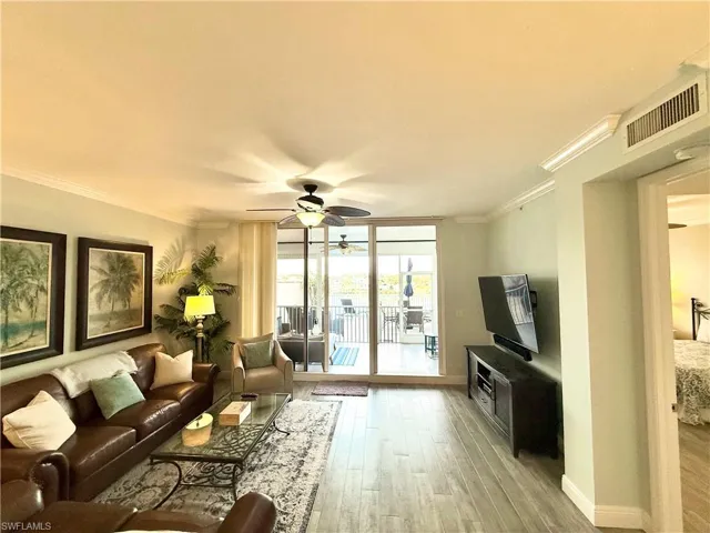Living area with ornamental molding, a ceiling fan, light wood-style floors, and a wall of windows
