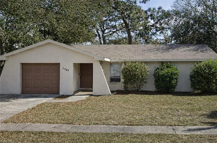 Ranch-style home with stucco siding, a front yard, concrete driveway, and an attached garage