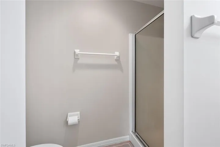 Bathroom featuring baseboards, toilet, and a shower stall