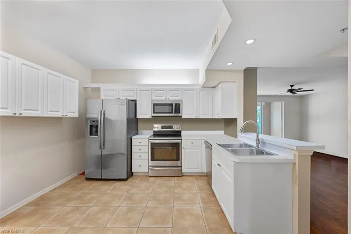 Kitchen featuring a peninsula, light tile patterned flooring, a sink, light countertops, and appliances with stainless steel finishes