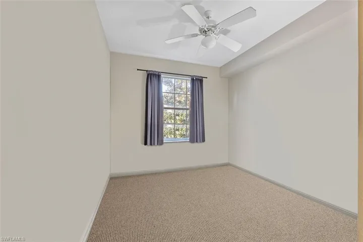 Carpeted spare room with baseboards and a ceiling fan