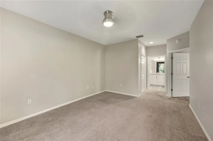 Carpeted interior space featuring light neutral wall tones and a ceiling-mounted light fixture