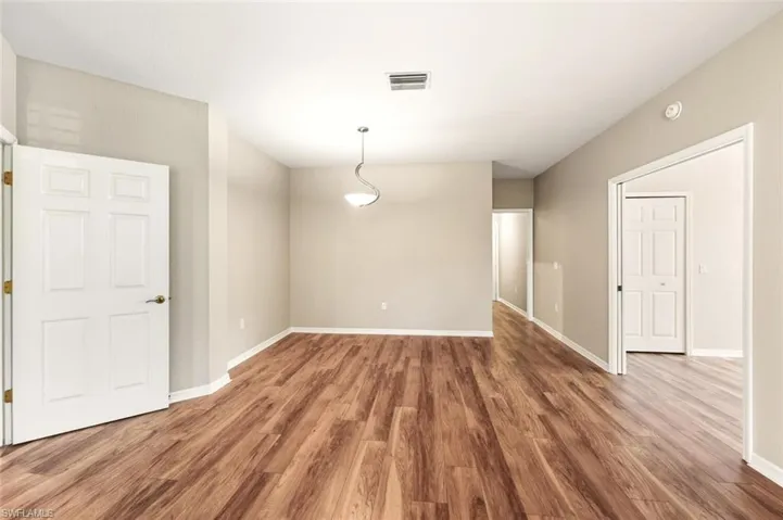 Spacious room featuring wood-finish flooring, neutral-toned walls, and white baseboards