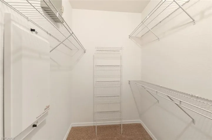 Walk-in closet featuring wire shelving systems, a freestanding wire shelving unit, and textured carpet flooring