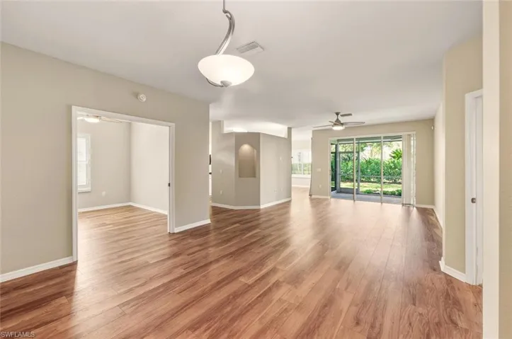 Expansive open-concept living area featuring wood-finish flooring, neutral wall tones, and recessed ceiling details