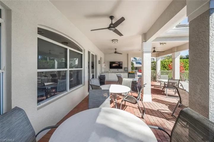 Covered outdoor living area featuring a brick paver patio, multiple ceiling fans, recessed lighting, and an outdoor built-in entertainment center