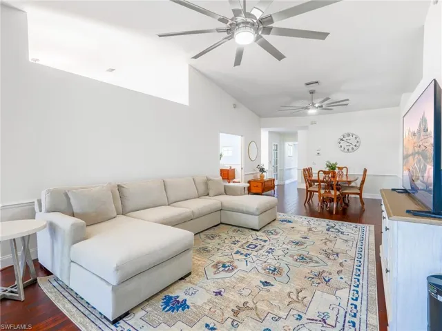 Living area featuring dark wood-type flooring, vaulted ceiling, and a ceiling fan