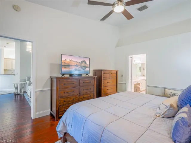 Bedroom with dark wood-type flooring, a ceiling fan, and ensuite bathroom