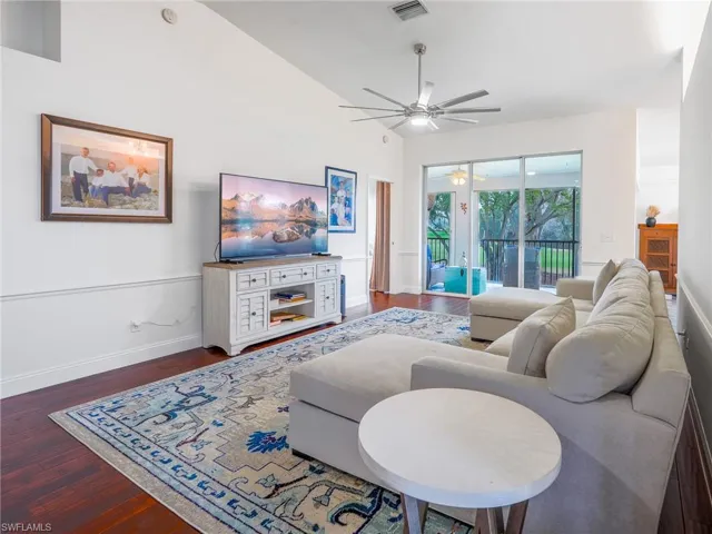 Living area featuring dark wood-type flooring, a ceiling fan, and vaulted ceiling