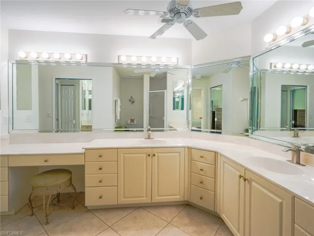Bathroom with double vanity, a shower stall, and light tile patterned flooring