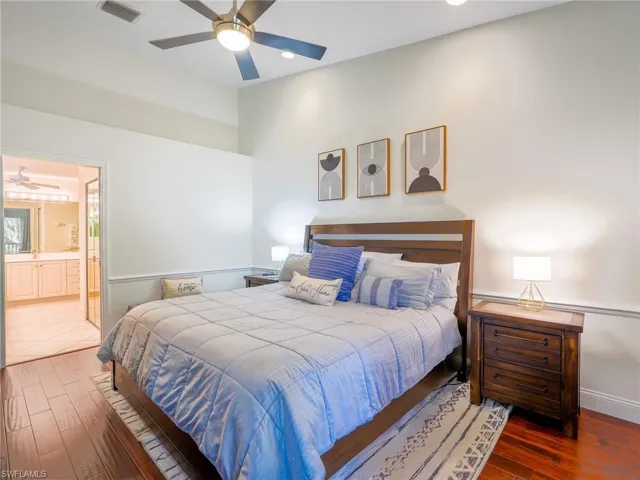 Bedroom featuring dark wood finished floors, ceiling fan, and ensuite bathroom