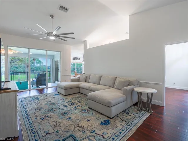 Living room featuring dark wood-style floors, ceiling fan, and vaulted ceiling