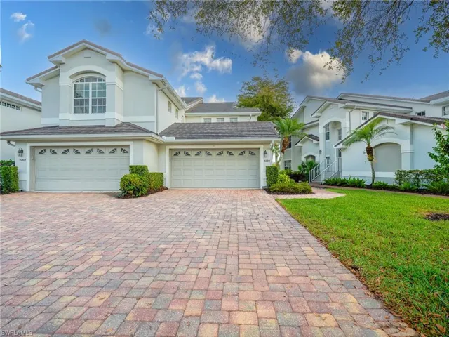 Traditional home featuring stucco siding, driveway, and a front lawn