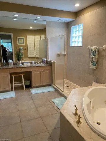 Full bath featuring a jetted tub, vanity, a walk in shower, and recessed lighting