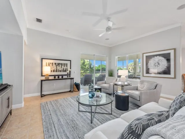 Living room with crown molding, light tile patterned floors, and ceiling fan