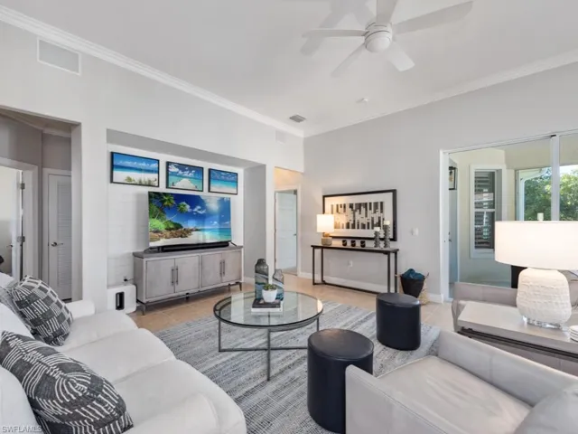 Living room with crown molding, light tile patterned floors, and ceiling fan