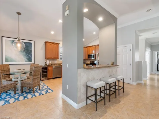 Kitchen featuring ornamental molding, stainless steel appliances, beverage cooler, and light tile patterned floors