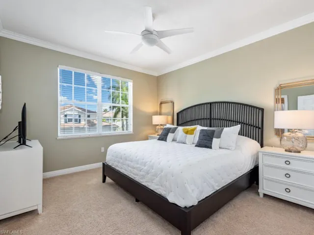 Carpeted bedroom with ceiling fan and ornamental molding