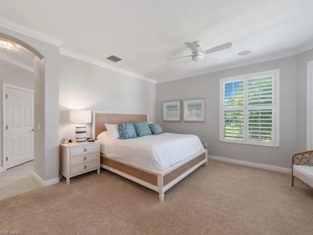 Carpeted bedroom featuring ceiling fan and ornamental molding