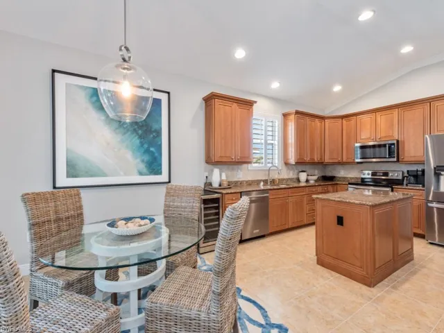 Kitchen featuring dark stone countertops, stainless steel appliances, decorative light fixtures, a kitchen island, and decorative backsplash
